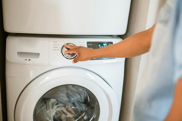 A person stands beside a washing machine in a laundry room